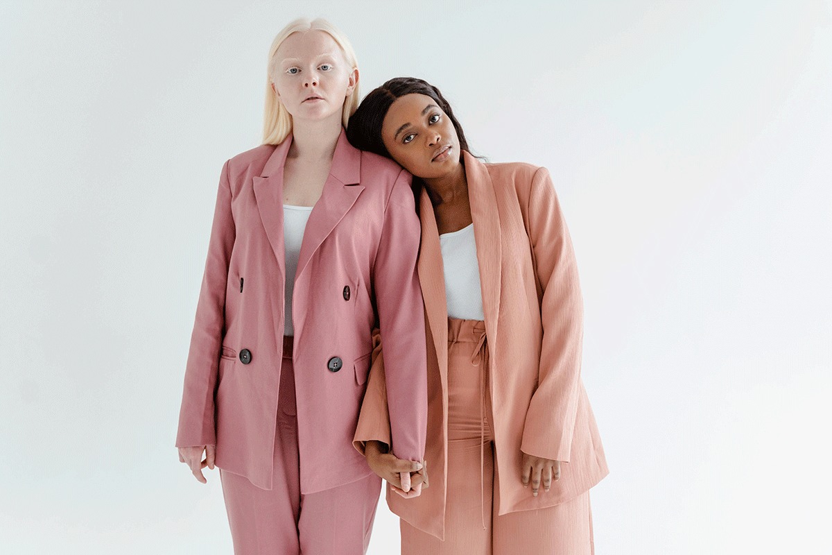 Two models in pink suits photographed against a plain white background