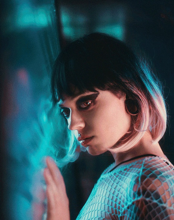 Woman with a dark bob lit in teal