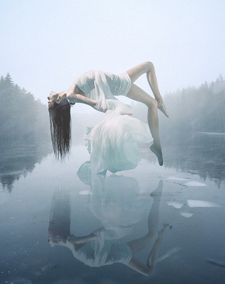 Woman levitating above the ice with a hand-built reflection, fog and custom-brush snow, using manual compositing in Photoshop