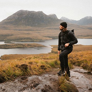 Hiker in a black beanie standing above a mountain lake, course thumbnail for Master Color Theory & Composition in Photoshop
