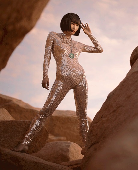 Woman in a sequinned jumpsuit posed on a desert rock