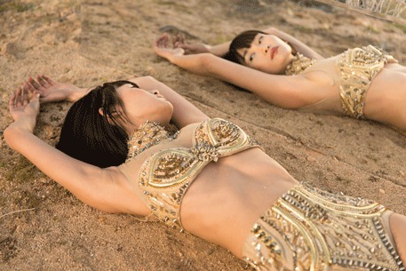 Woman in a gold chain top lying on warm desert sand