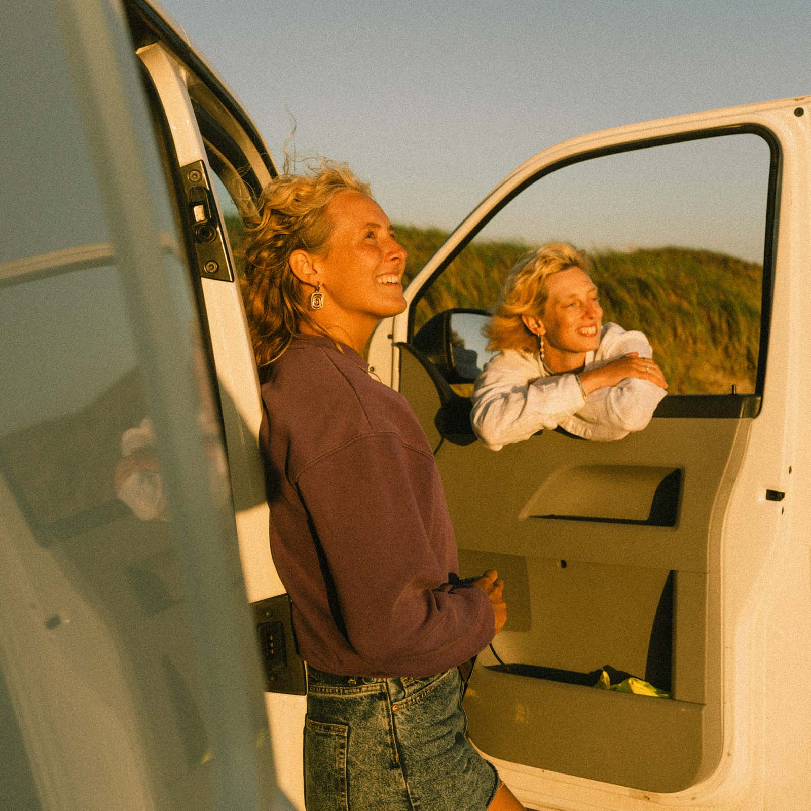A backlit portrait of two women leaning out of a van door at sunset, before any skin tone correction using the Camera Raw Vectorscope