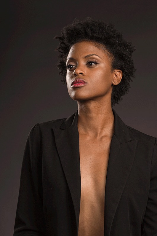 Woman in an open black blazer against a dark background