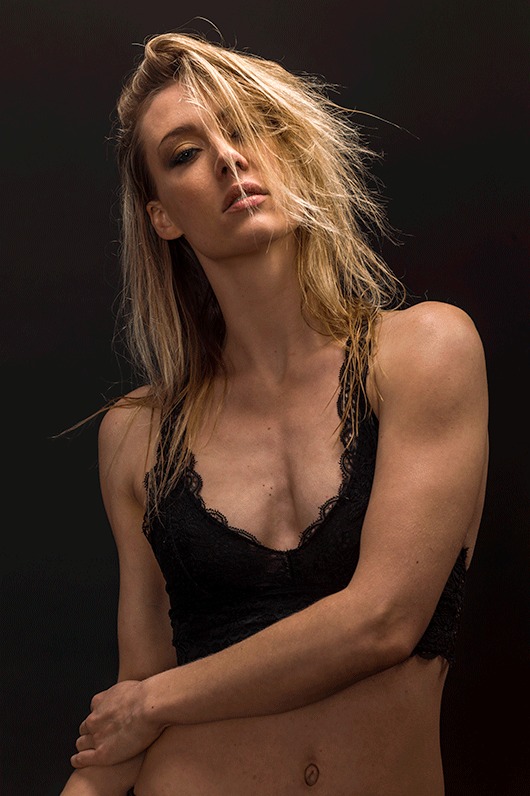 Blonde woman in a black top photographed against a dark background