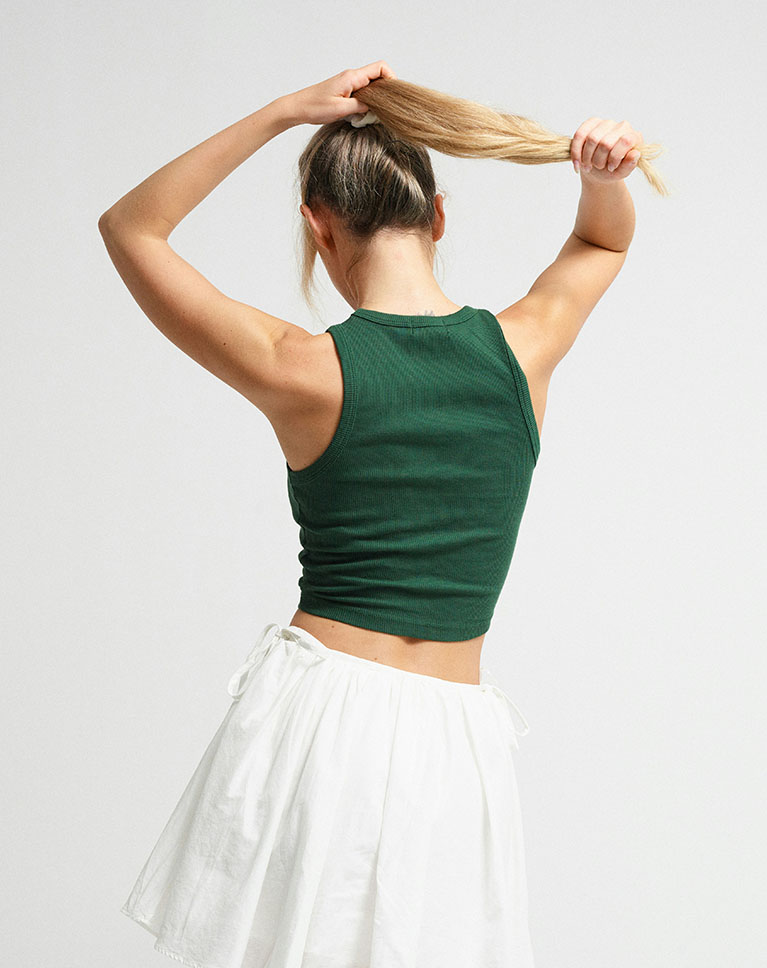 A woman in a green tank top and white skirt, seen from behind