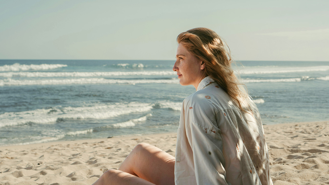 The same beach portrait after masking in Photoshop: distractions removed, subject brightened and background darkened