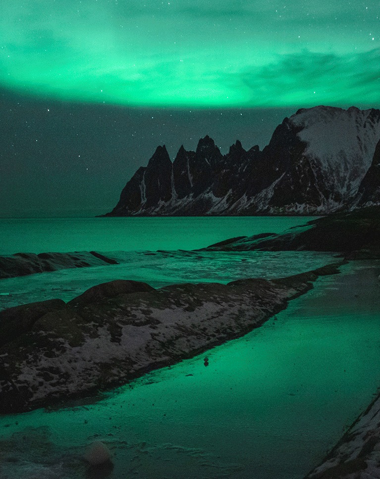 Aurora over a dark rocky coastline — the base landscape plate before compositing