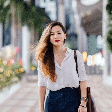 Woman in a white blouse walking down a city street carrying a bag, demonstrating intermediate object removal in Photoshop