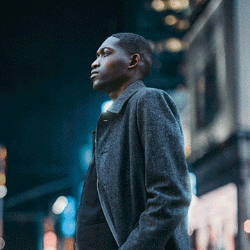 Man in a gray coat standing and looking away on a city street at night, demonstrating how to quickly change backgrounds in Photoshop