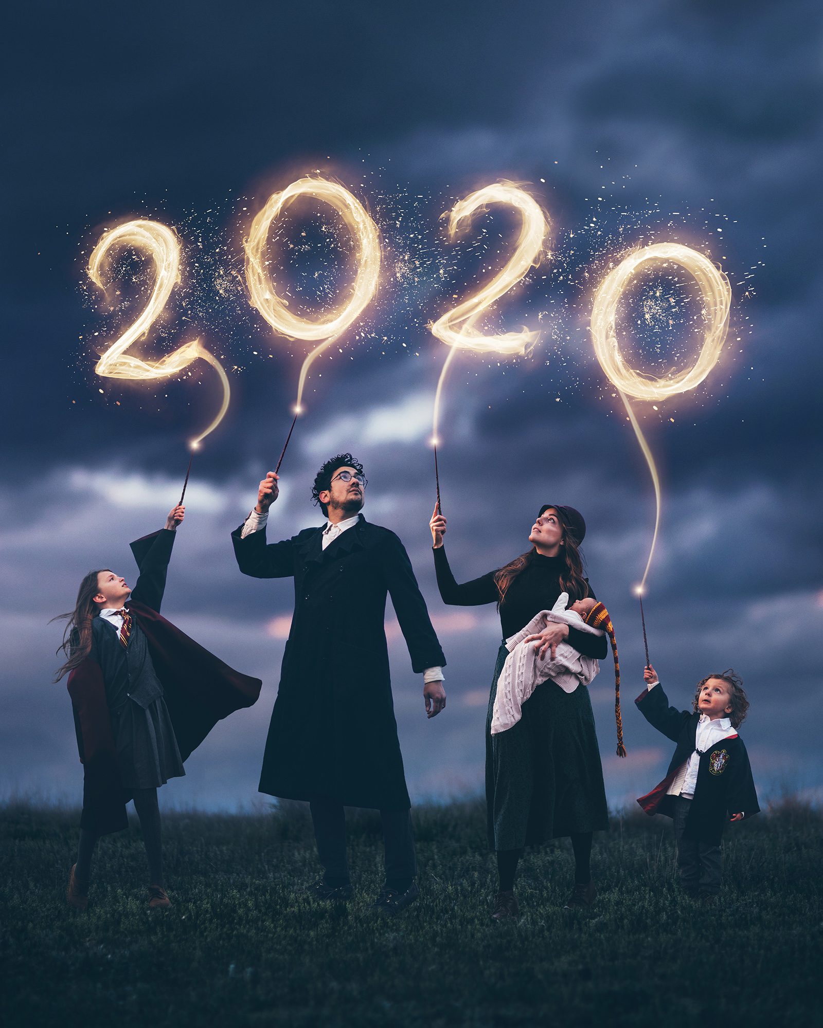 Alexandria's family in wizard robes on a hill at dusk, writing 2020 in the sky with sparkling wands