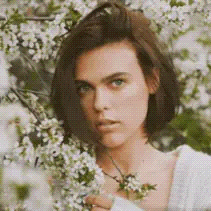 Animated cinemagraph of a woman with short brown hair among white blossoming flowers, thumbnail for a tutorial on creating a cinemagraph in Photoshop and After Effects