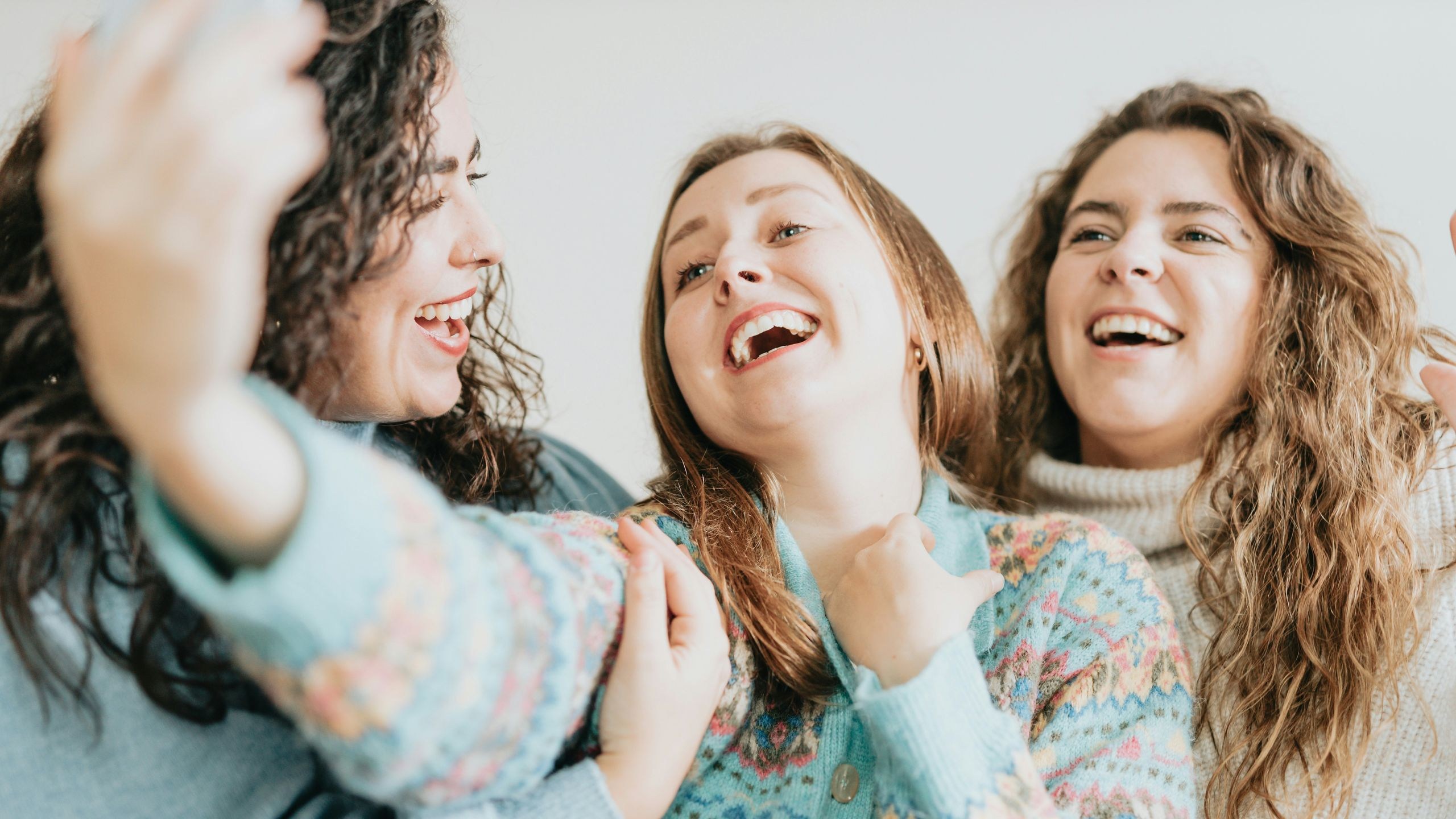 Three friends laughing on a couch after Lightroom Open Eyes, all eyes open