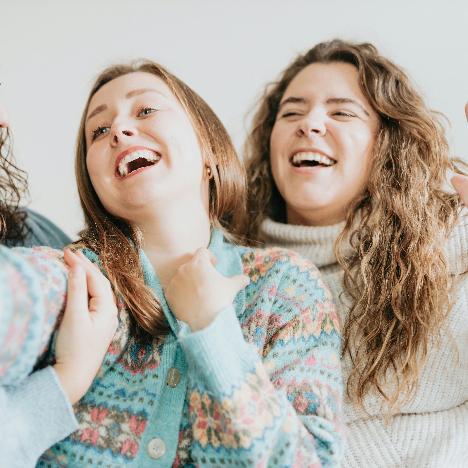 Two friends laughing on a couch before Lightroom Open Eyes, the woman on the right with her eyes shut mid-laugh