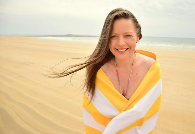 Woman wrapped in a striped beach towel on the sand