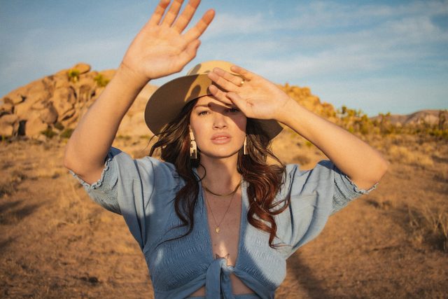 Woman in a hat shading her eyes in a sunny desert