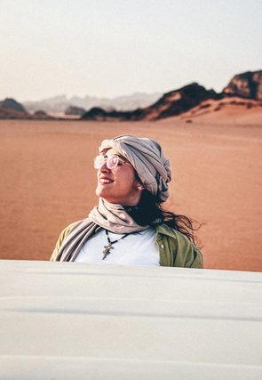 Smiling woman in a headscarf and glasses in a red desert
