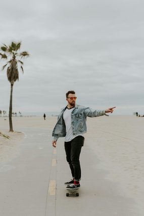 Man riding a skateboard along a beach path