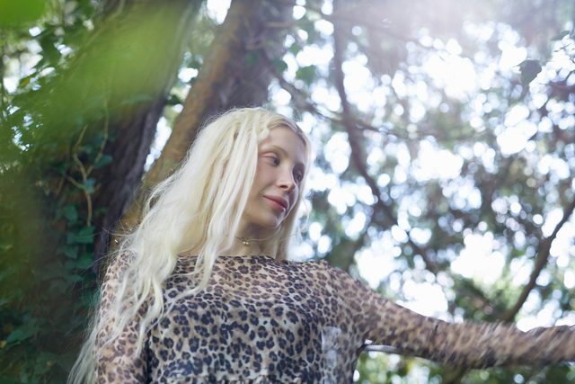 Blonde woman in a leopard print top under trees