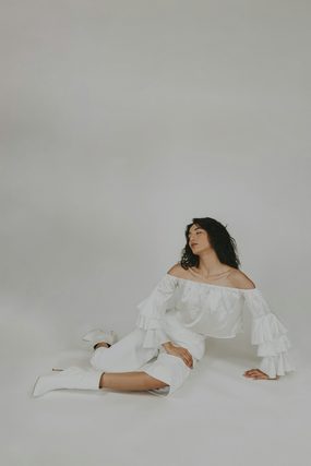 Woman in a white ruffled outfit sitting on a studio floor