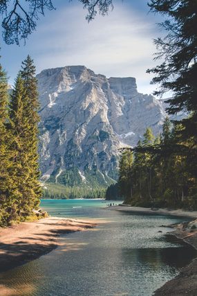 Mountain lake framed by pine trees under a rocky peak
