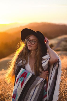 Woman in a hat and glasses at sunset