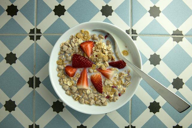 Bowl of muesli with strawberries on blue patterned tiles