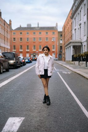 Young woman in a white jacket standing in a city street