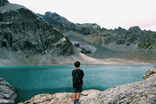 Young hiker with a backpack at a turquoise mountain lake