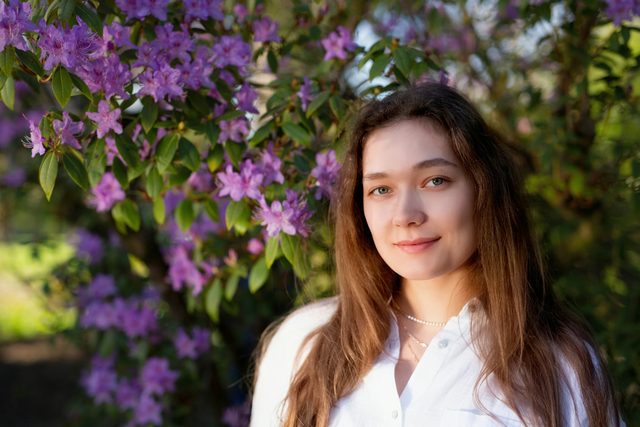 Young woman in a white shirt beside a purple flowering bush