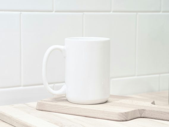 White mug on a wooden cutting board against white tiles