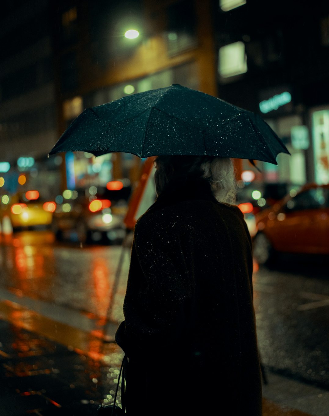 Before: a woman with an umbrella on a city street at night