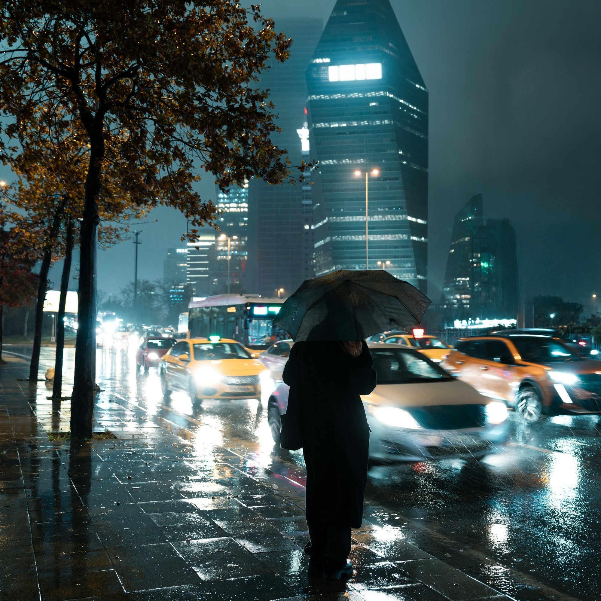 Before: a person with an umbrella on a wet city sidewalk at night