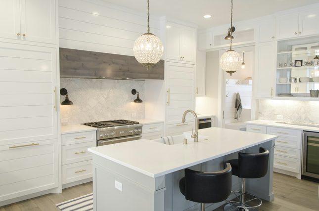 White kitchen with a marble island and globe pendant lights