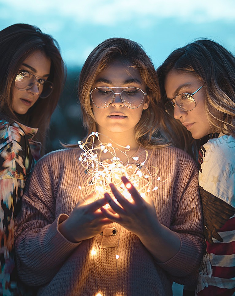 Smart Dodge and Burn Photoshop action after: three friends lit by fairy lights, faces lifted