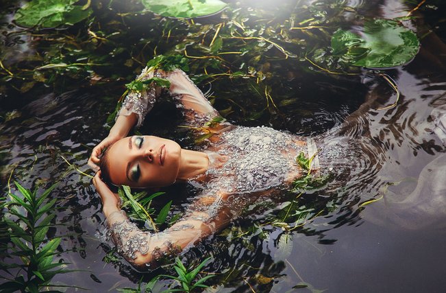 Woman lying in water among leaves