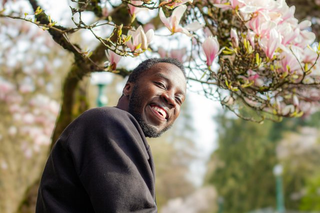 Smiling man under a tree with pink magnolia blossoms