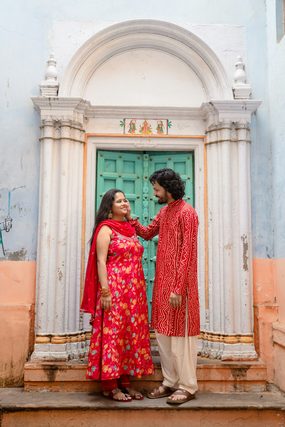 Couple in red traditional Indian clothes at an ornate green doorway