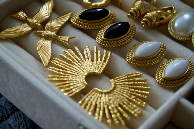 Gold earrings with pearls and black stones in a jewelry box