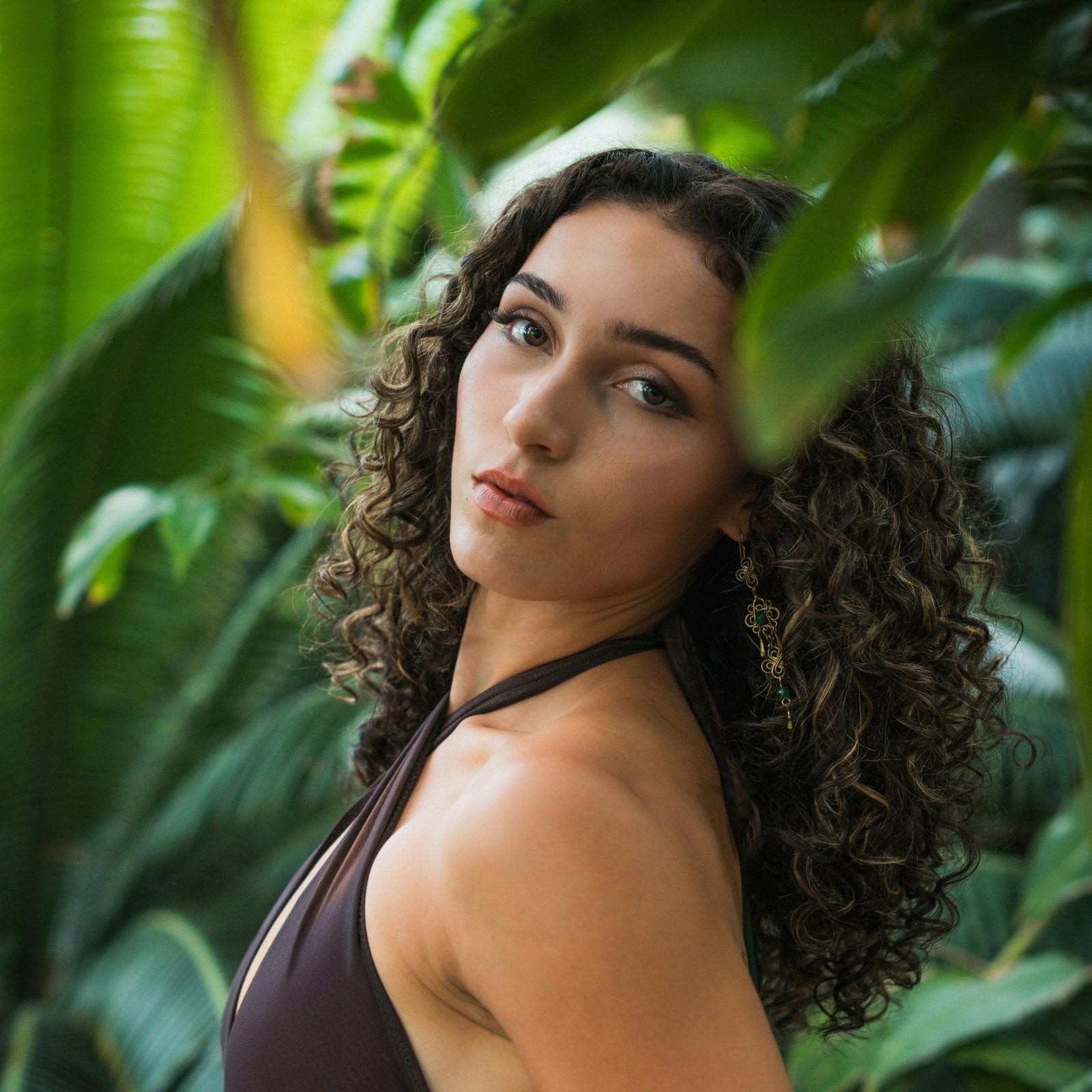 Portrait of a woman with curly hair among tropical leaves before editing, from the Photoshop 2026 tips tutorial