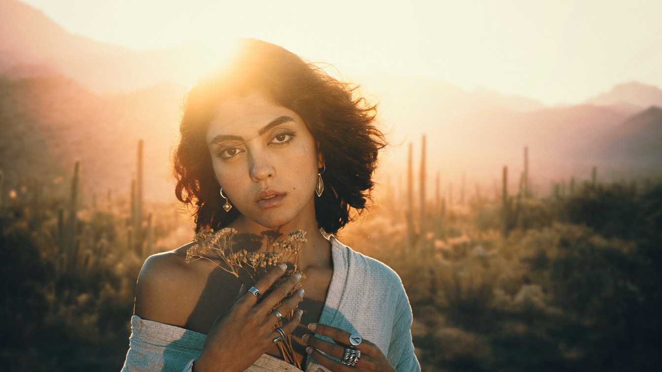 The same desert portrait after a warm color grade with the Protect Skin action: golden light and deeper shadows, with her skin still natural