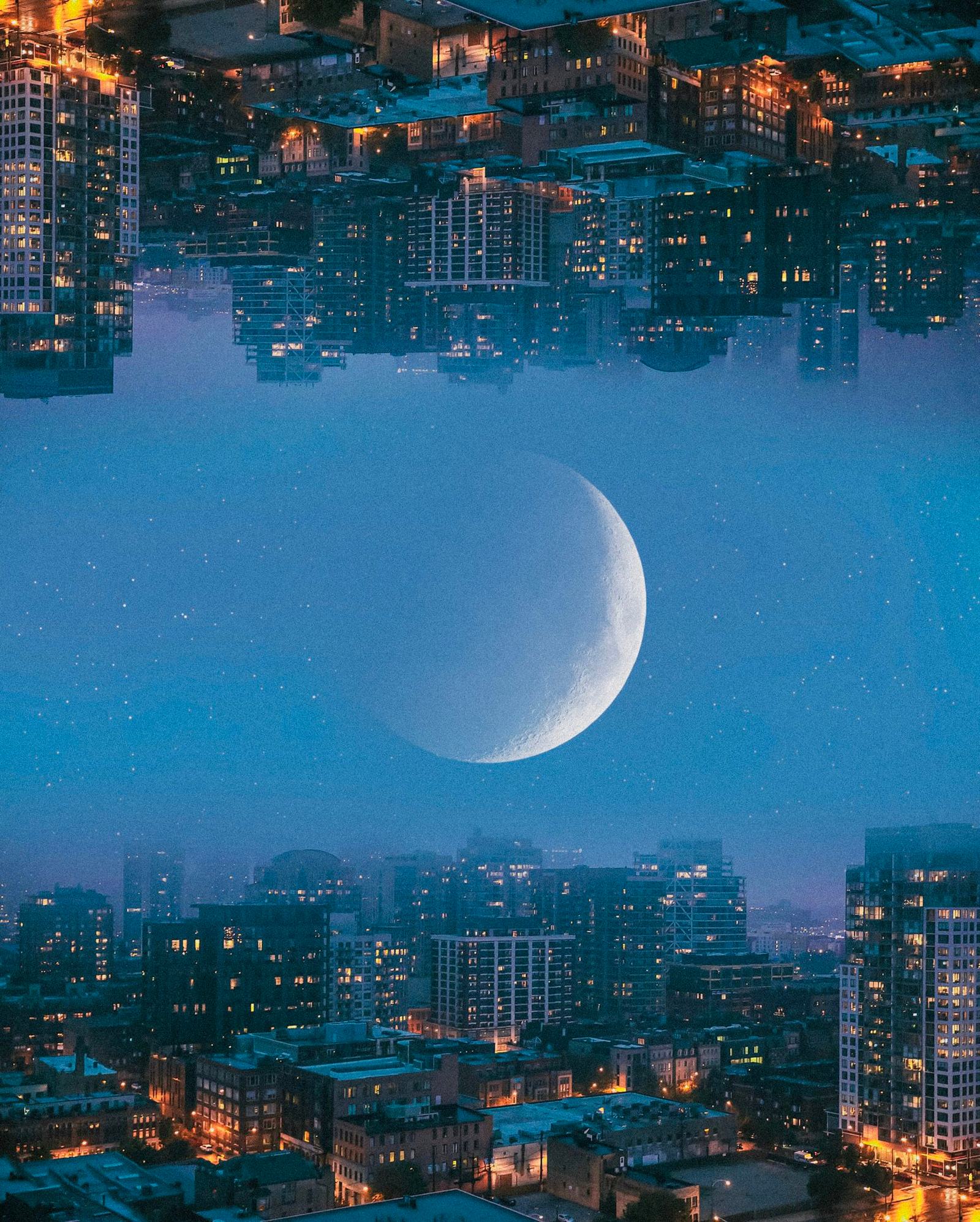Composite of a city at dusk mirrored upside down across the sky, with a large crescent moon between the two skylines