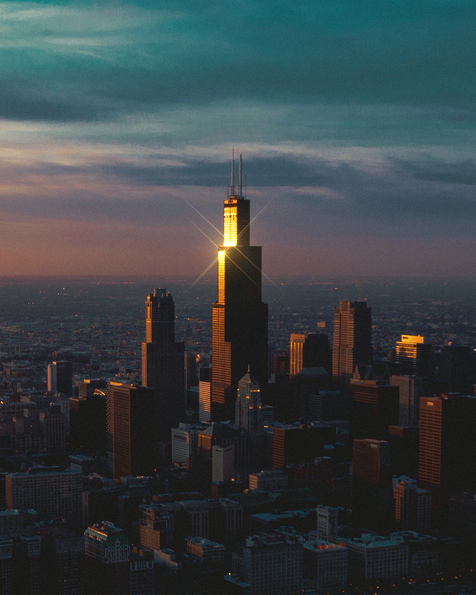 Chicago skyline at dusk with the sun glinting off the side of the Willis Tower