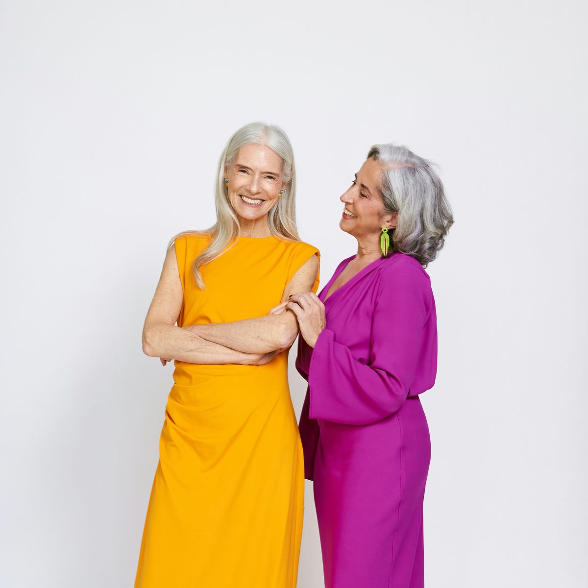 Two women in a studio, one in a long yellow dress and one in a magenta dress
