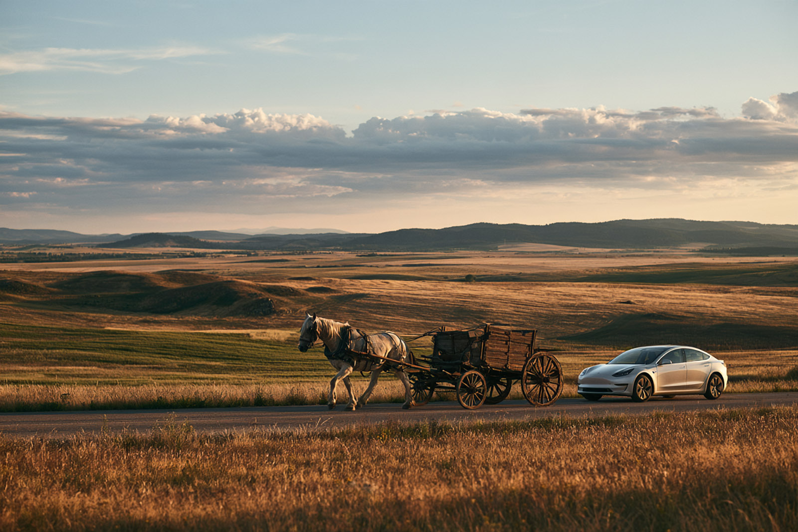 A horse-drawn cart and a modern car side by side on a country road