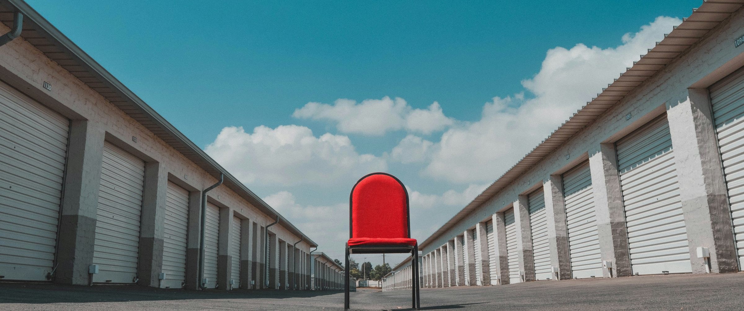 Leading lines in photography: two rows of storage units converge on a red chair under a blue sky
