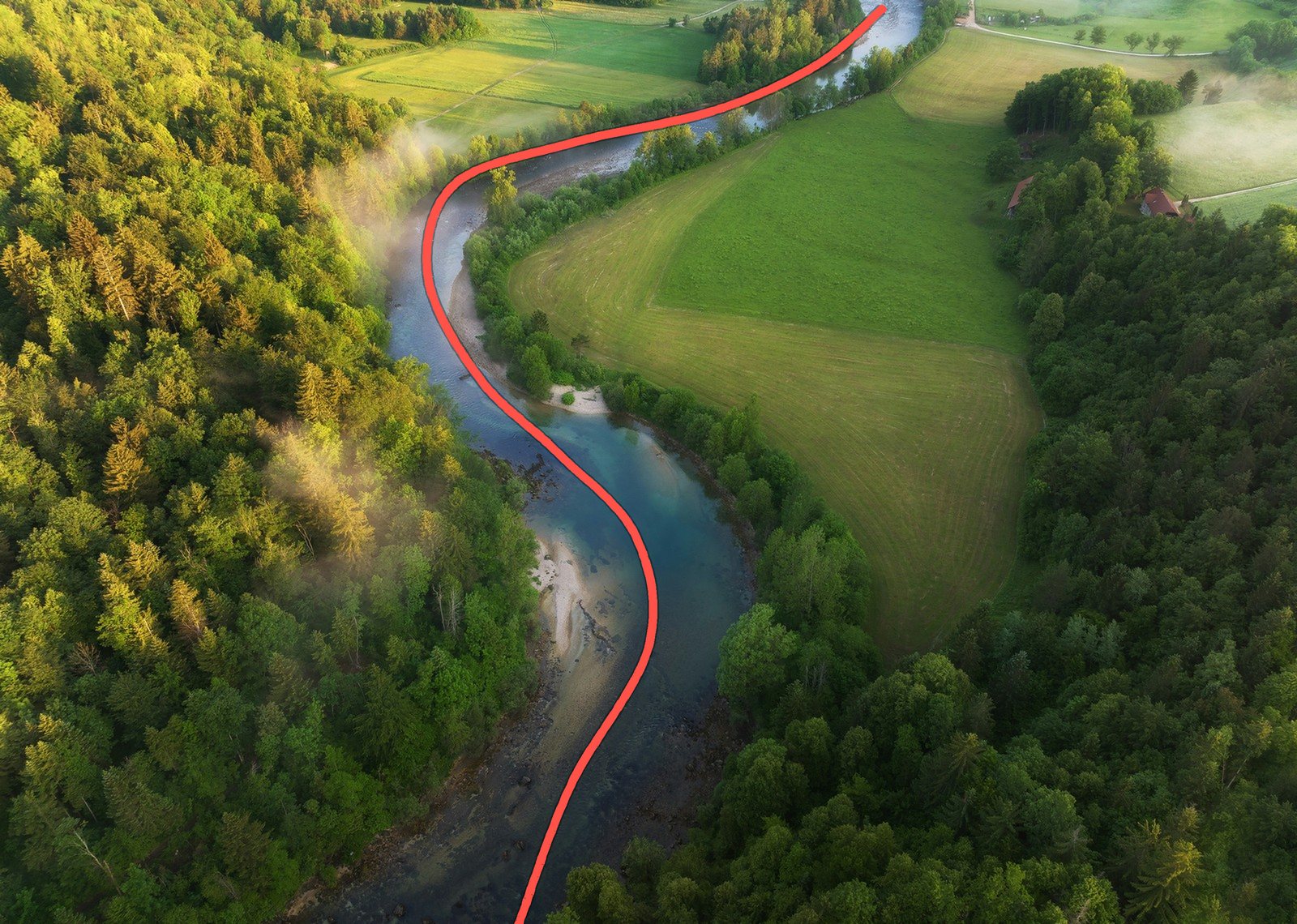 Aerial view of a river curving in an S-shape through a green forest and fields