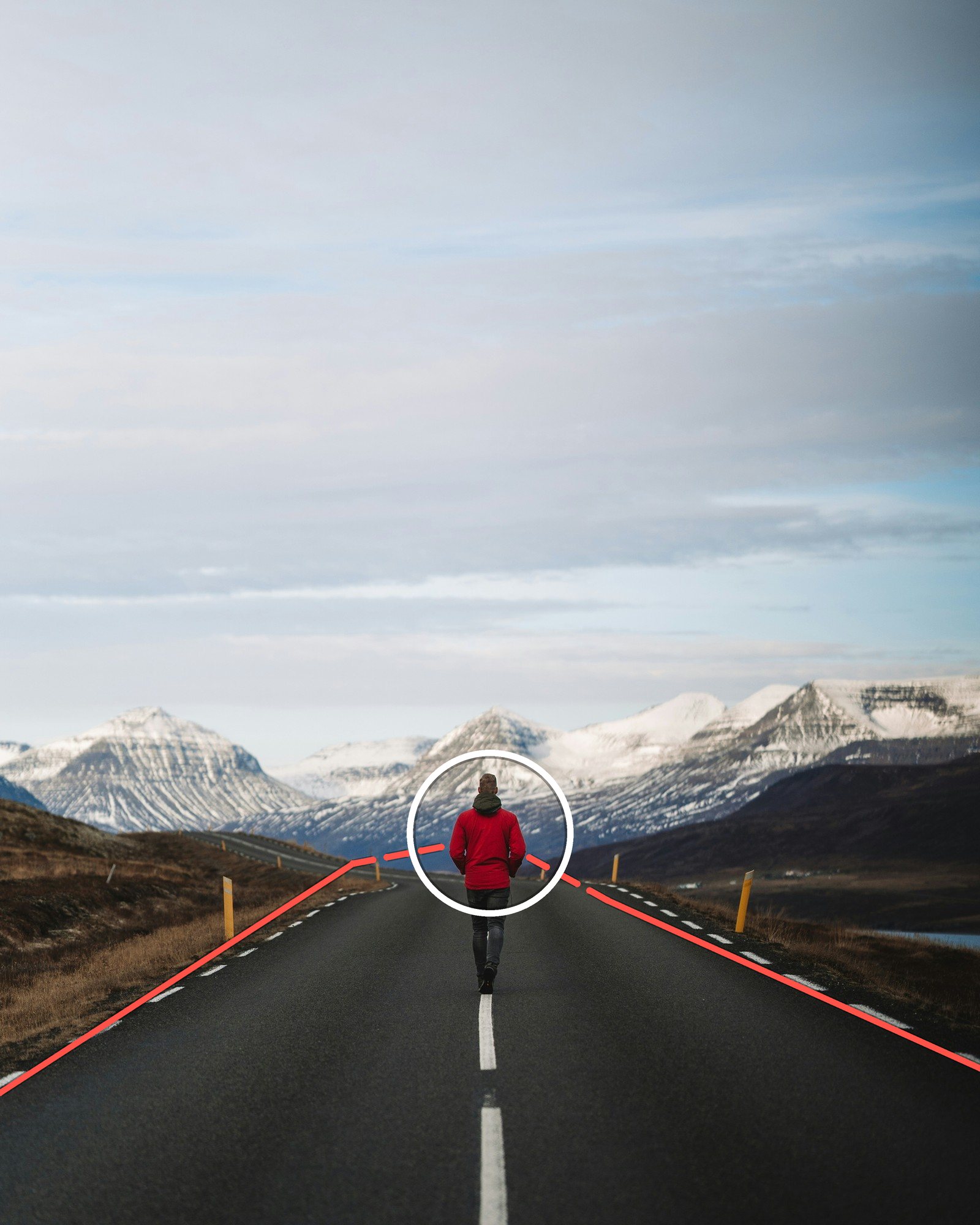 A person in a red jacket walking down the center of a road toward snowy mountains, with the road edges converging on them