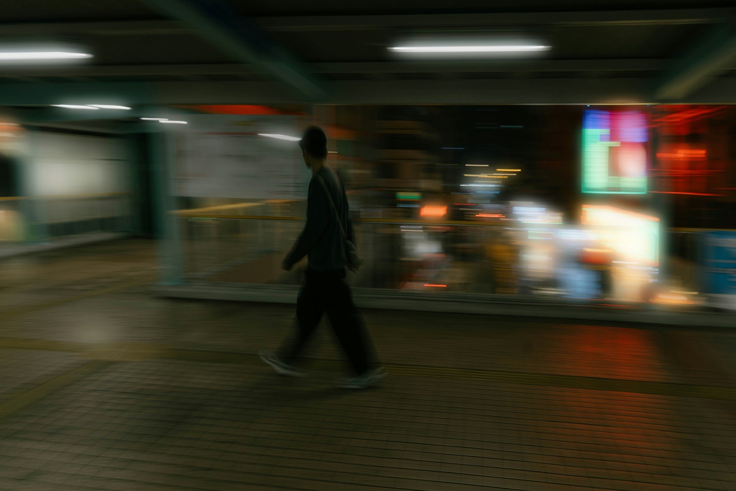 Motion-blurred photo of a person walking through an underpass at night