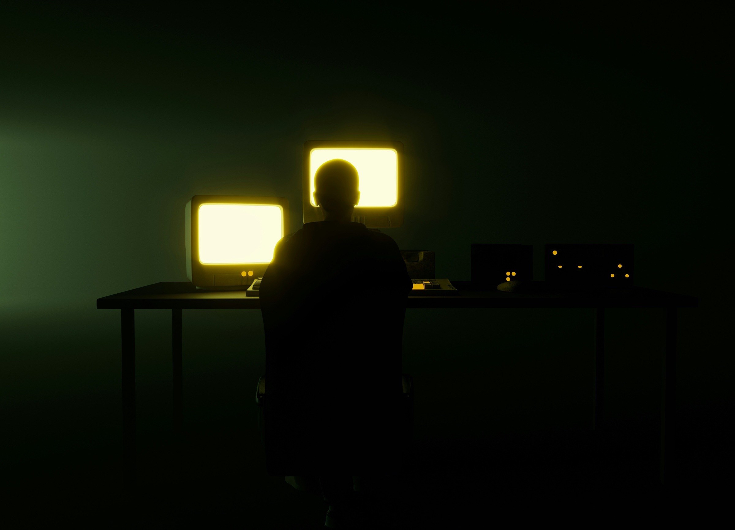 Person working at two glowing monitors in a dark room